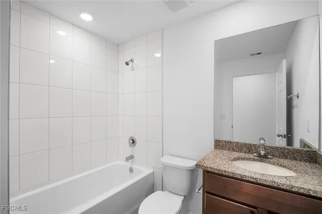 a bathroom with a granite countertop sink toilet mirror and bathtub