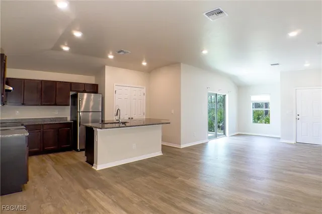 a kitchen with stainless steel appliances kitchen island granite countertop a stove a sink and a refrigerator