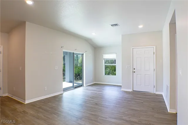 a view of an empty room with wooden floor and windows