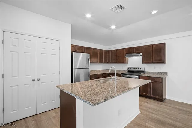 a kitchen with stainless steel appliances granite countertop a sink a stove a refrigerator a center island and cabinets