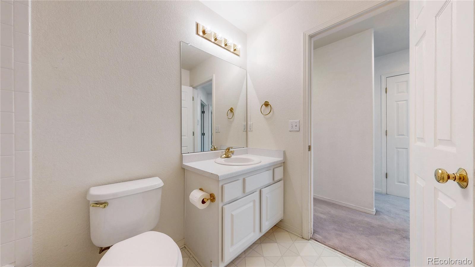 4367 Quail Street Wheat Ridge, CO 80033 - Photo 28 of 50 a bathroom with a sink a toilet and mirror