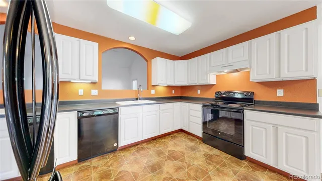 a kitchen with granite countertop a refrigerator stove and sink