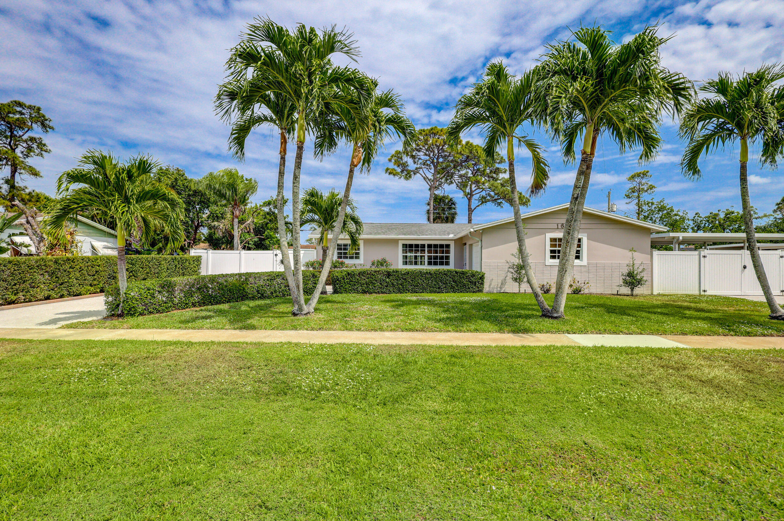 1618 Maypop Road West Palm Beach, FL 33415 - Photo 2 of 81 a front view of yellow house with a yard and palm trees