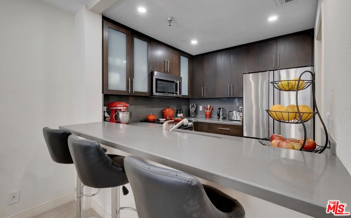 121 South Hope Street, Unit 313 Los Angeles, CA 90012 - Photo 6 of 35 a kitchen with stainless steel appliances a sink a stove and a refrigerator