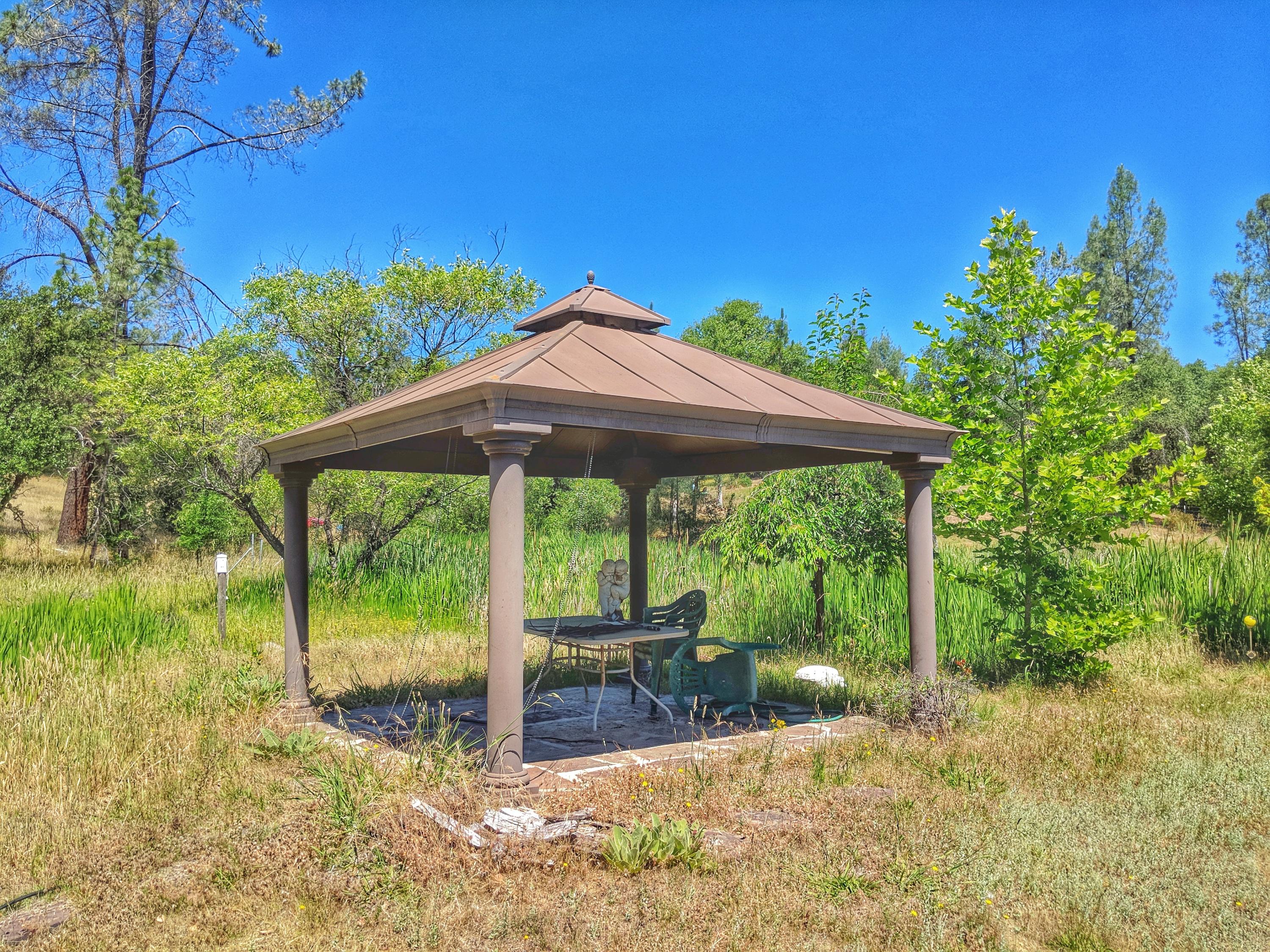 6818 Rector Creek Road Igo, CA 96047 - Photo 29 of 34 a backyard of a house with table and chairs under an umbrella