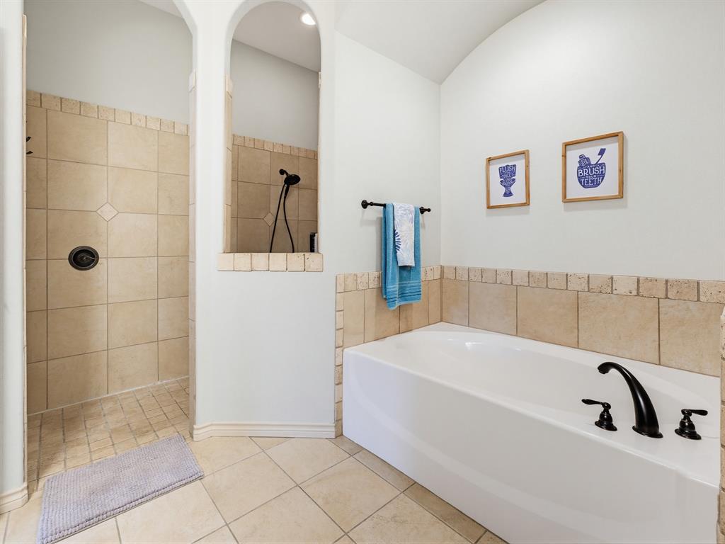 2108 Ridgewood Drive Bridgeport, TX 76426 - Photo 22 of 35 Bathroom featuring a white drop-in tub with a tile surround, a single vanity with integrated dual sinks, a dark bronze faucet, and tile flooring