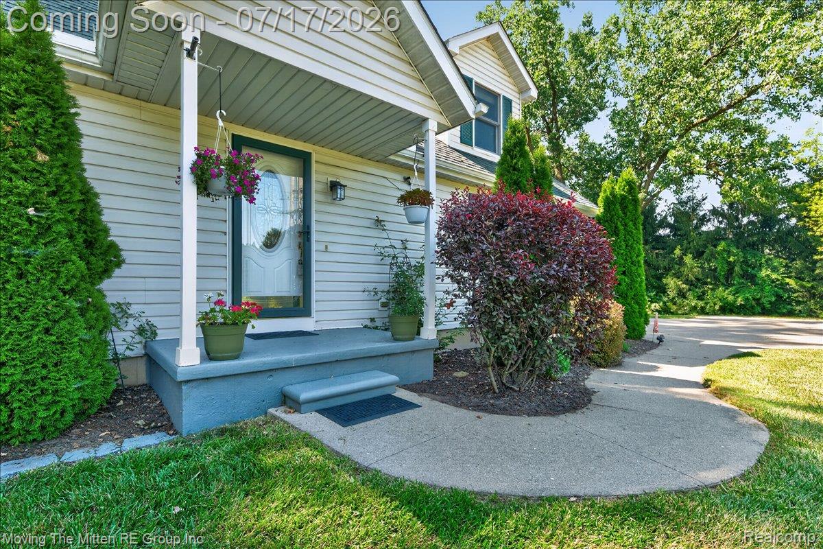 40162 Alden Road Belleville, MI 48111 - Photo 4 of 67 Entryway featuring a covered porch with a decorative glass front door, siding exterior, concrete steps, and a curved concrete walkway