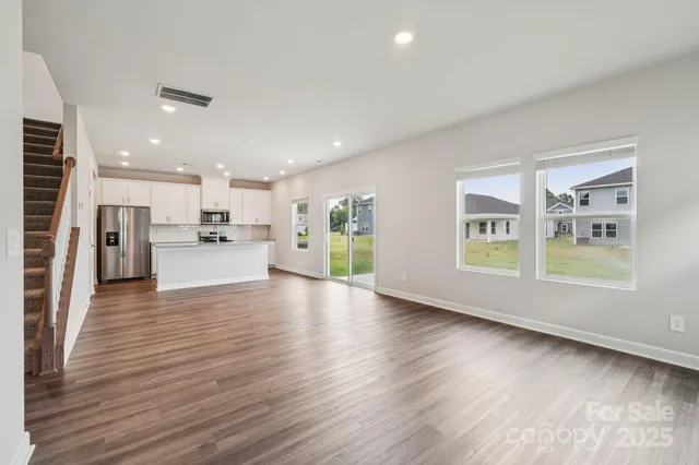 a view of empty room with wooden floor and windows