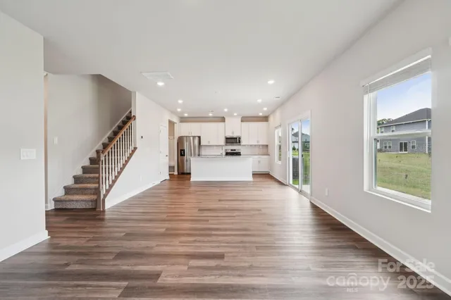 a view of a living room with kitchen and wooden floor