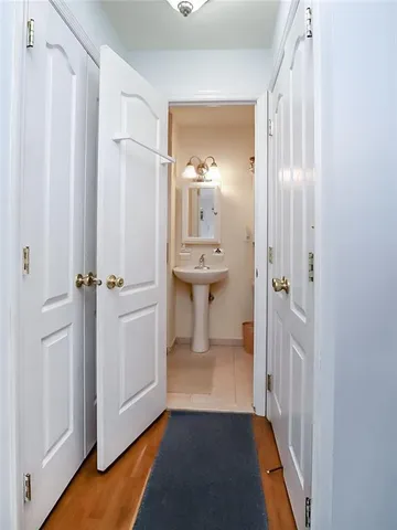 a view of a hallway with wooden floor and a bathroom