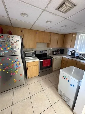 a kitchen with granite countertop a stove a sink dishwasher and a refrigerator with wooden floor