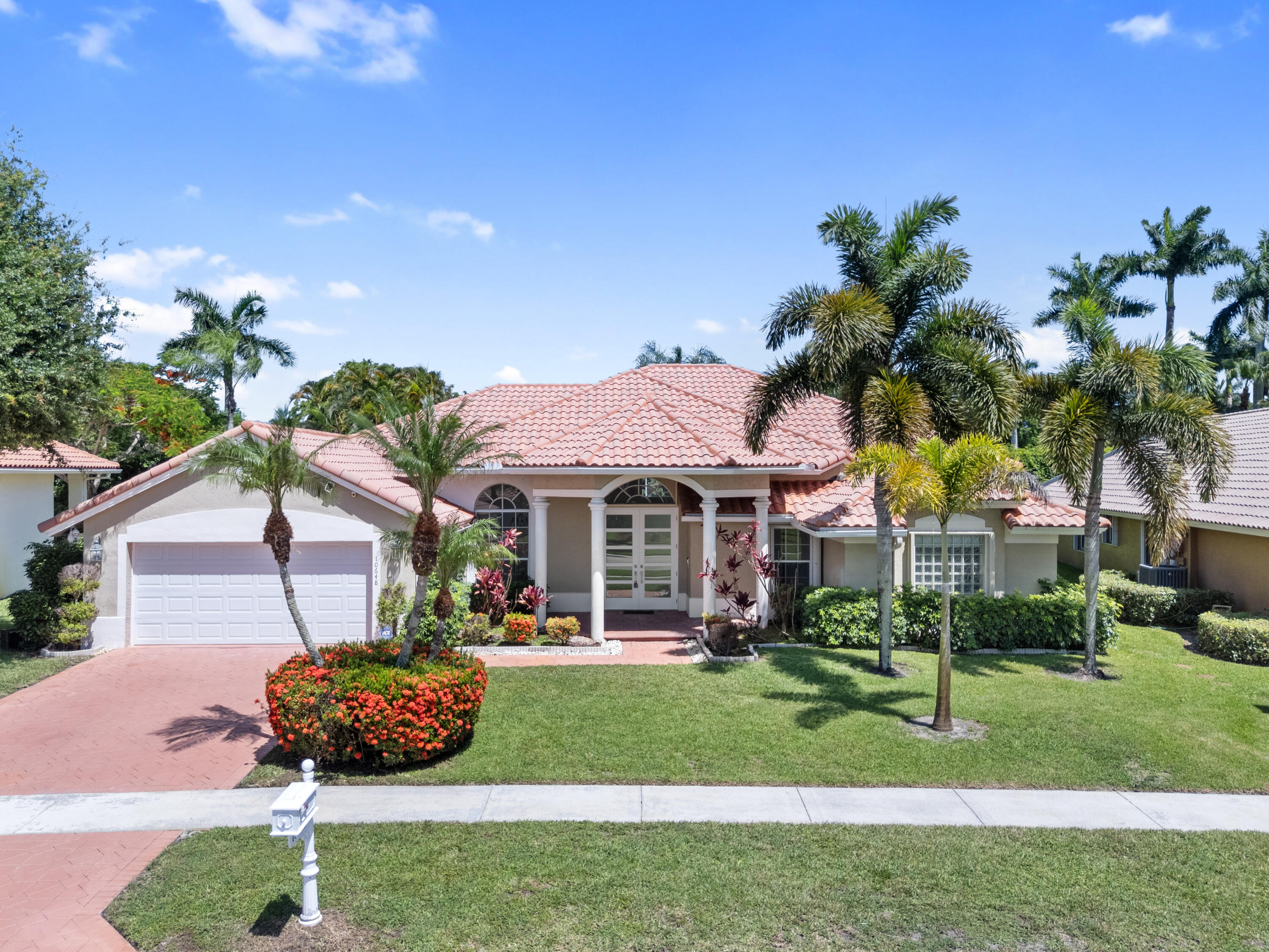 10648 Maple Chase Drive Boca Raton, FL 33498 - Photo 1 of 52 a front view of a house with a garden and plants