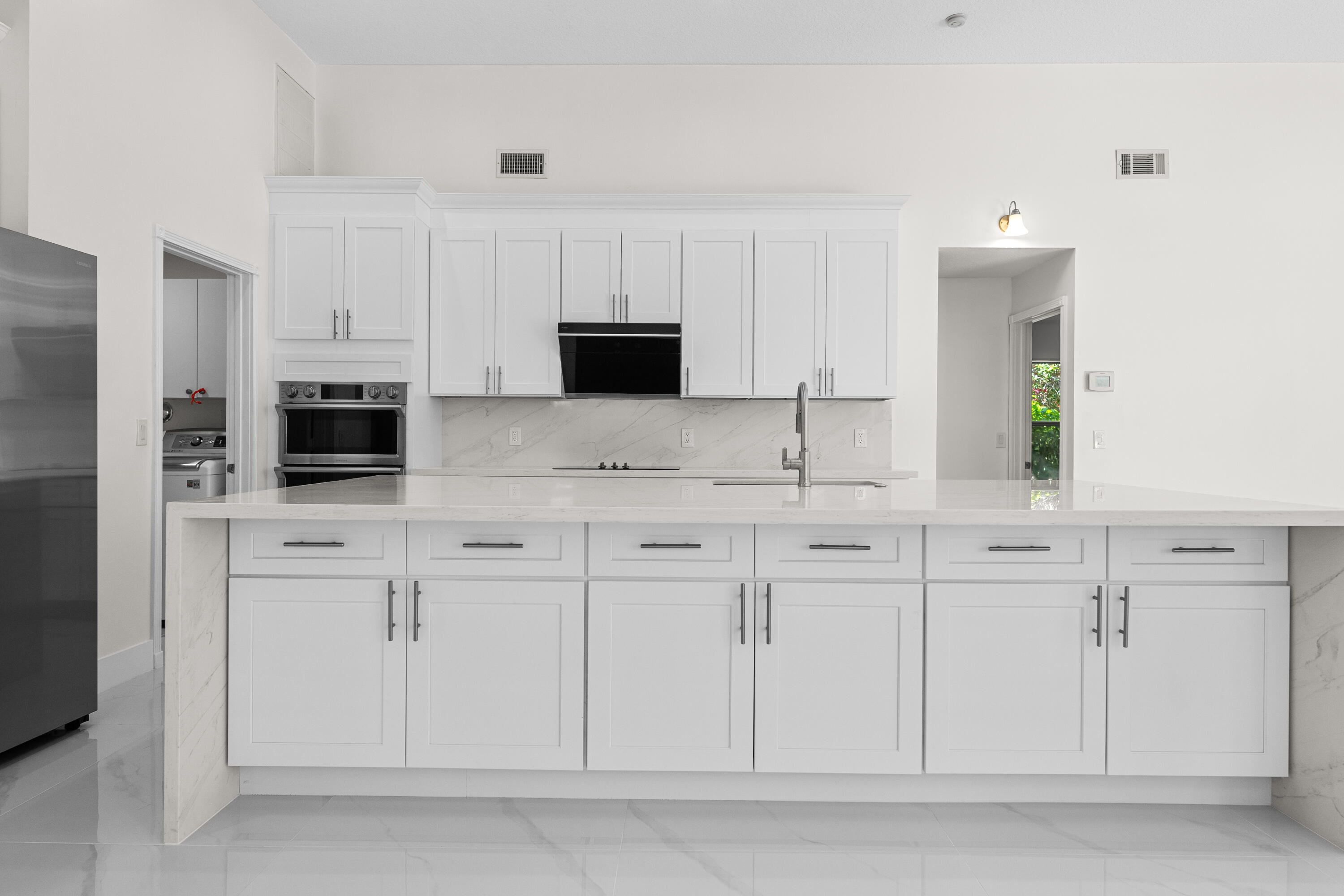 10648 Maple Chase Drive Boca Raton, FL 33498 - Photo 4 of 52 a kitchen with white cabinets and flat screen tv
