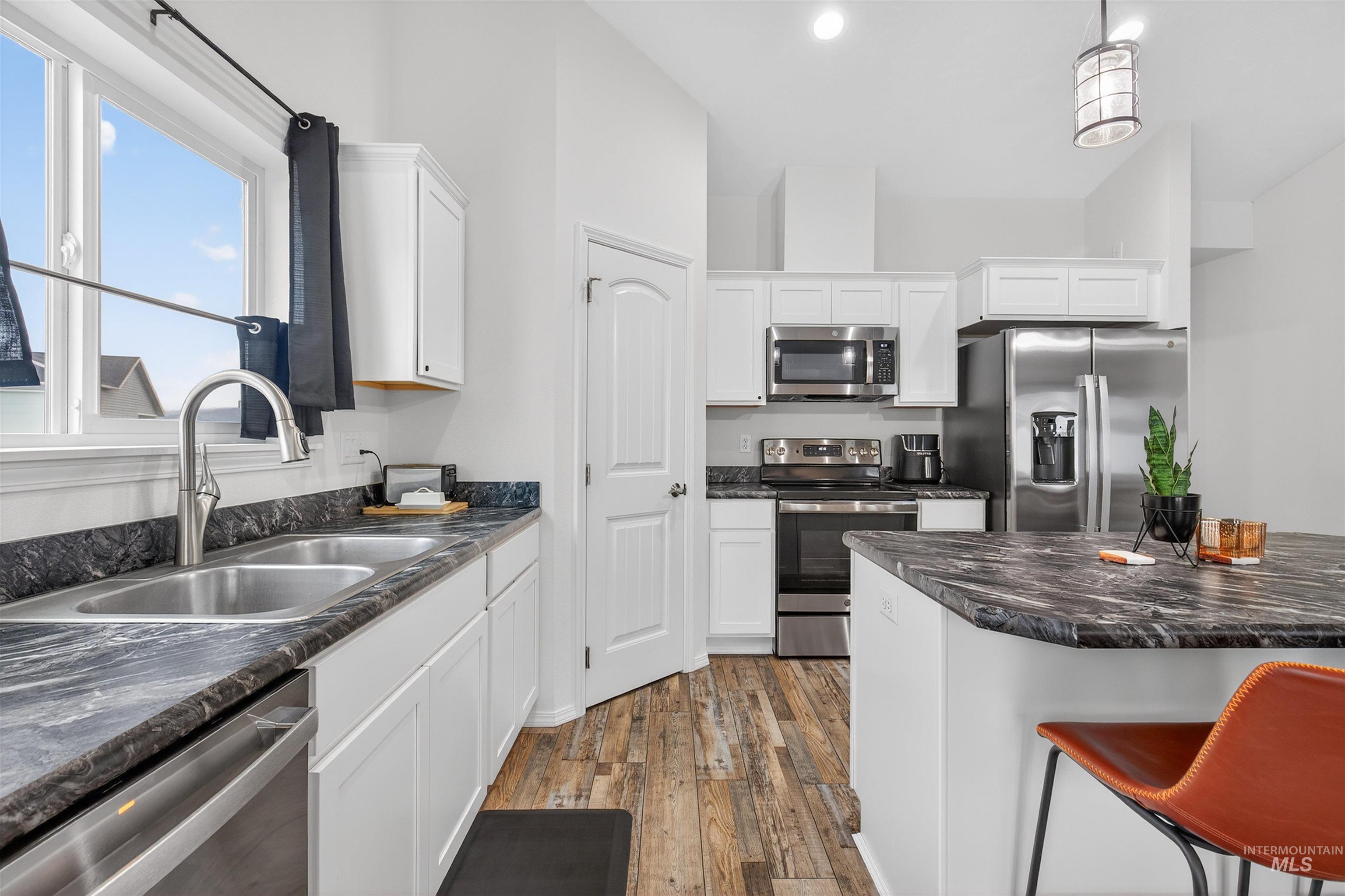 1432 Horizon Court Lewiston, ID 83501 - Photo 12 of 26 Kitchen featuring white cabinets, appliances with stainless steel finishes, decorative light fixtures, and a breakfast bar