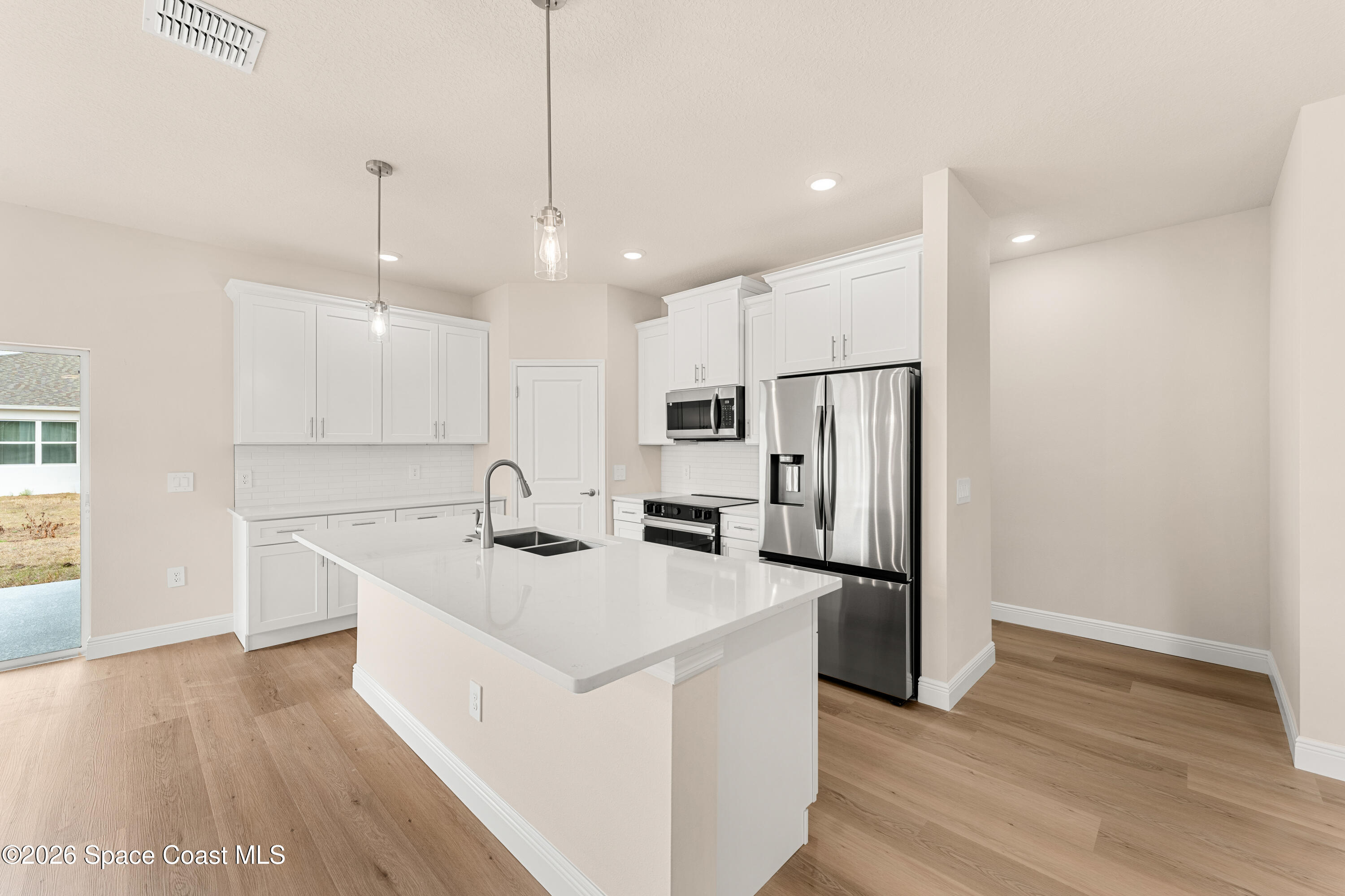 455 Mimosa Street Southwest Palm Bay, FL 32908 - Photo 13 of 43 a kitchen with stainless steel appliances granite countertop a refrigerator a sink a stove and white cabinets with wooden floor