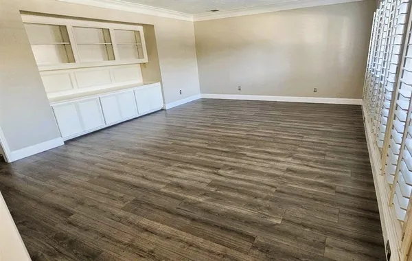 a view of an empty room with a window and wooden floor