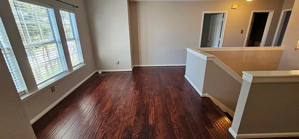 a view of an empty room with wooden floor and a window