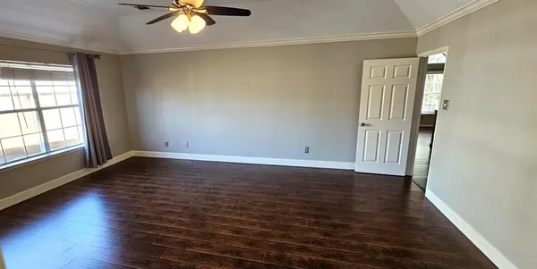 an empty room with wooden floor and chandelier fan