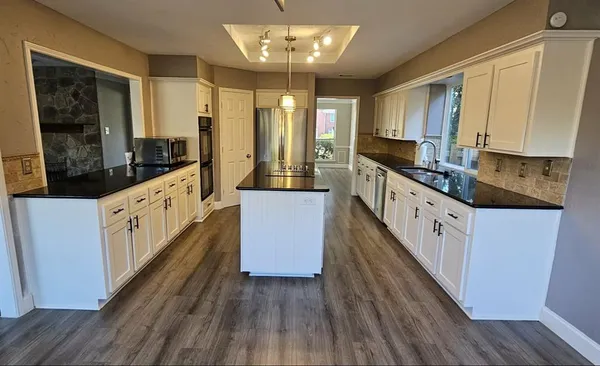 a large kitchen with wooden floor and white stainless steel appliances