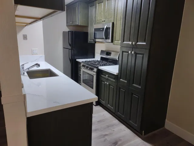 a kitchen with kitchen island granite countertop a sink stove and refrigerator