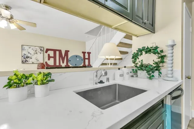 a kitchen with stainless steel appliances a sink a counter top space a window and a potted plant