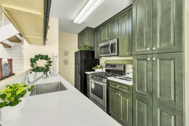 a kitchen with kitchen island granite countertop stainless steel appliances a sink a counter top space cabinets and a window