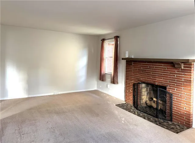 an empty room with windows and fireplace