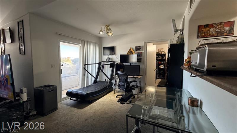 7255 West Sunset Road, Unit 2027 Las Vegas, NV 89113 - Photo 8 of 38 Sliding glass doors open to the outdoor patio, filling the carpeted space with natural light.