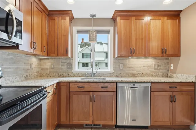 a kitchen with granite countertop wooden cabinets a sink and dishwasher a stove with wooden floor