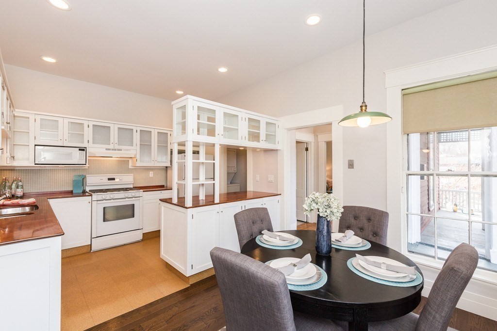 12 Willow Court, Unit A Arlington, MA 02476 - Photo 1 of 16 a kitchen with stainless steel appliances kitchen island granite countertop a stove a sink a dining table and chairs with wooden floor