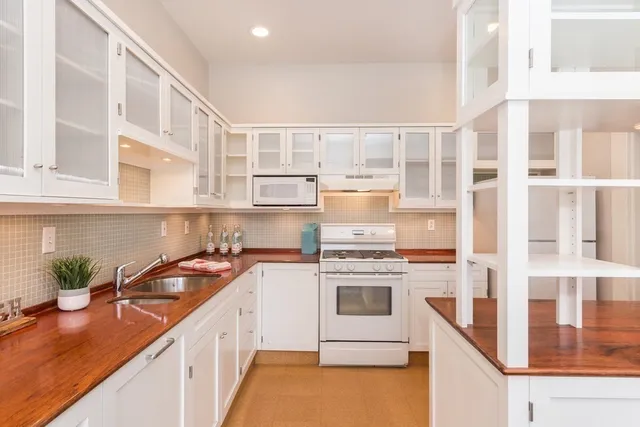 a kitchen with stainless steel appliances granite countertop a stove a sink and a white cabinets