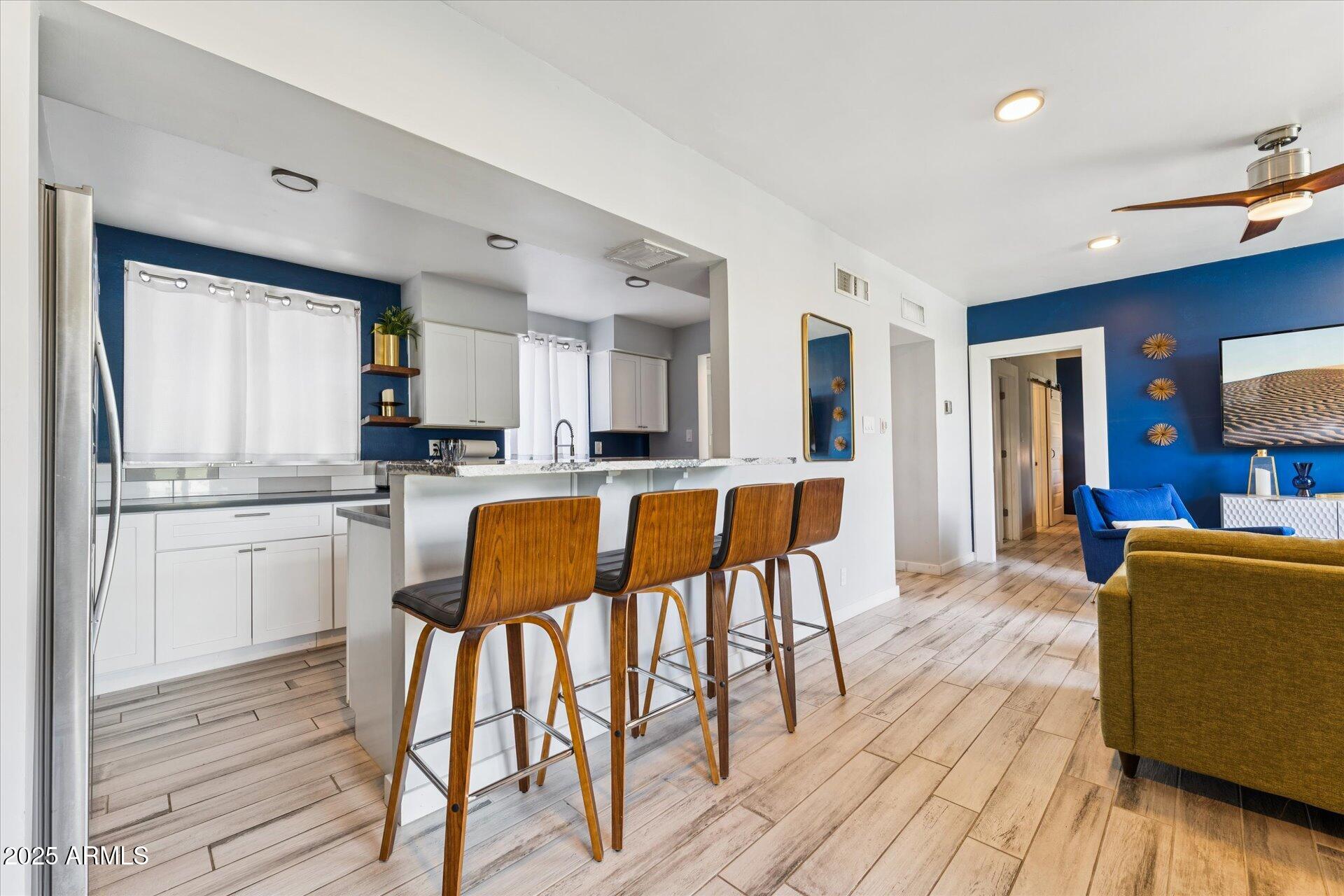 3242 East Camelback Road, Unit 105 Phoenix, AZ 85018 - Photo 11 of 24 a kitchen with stainless steel appliances kitchen island granite countertop wooden floors and white cabinets