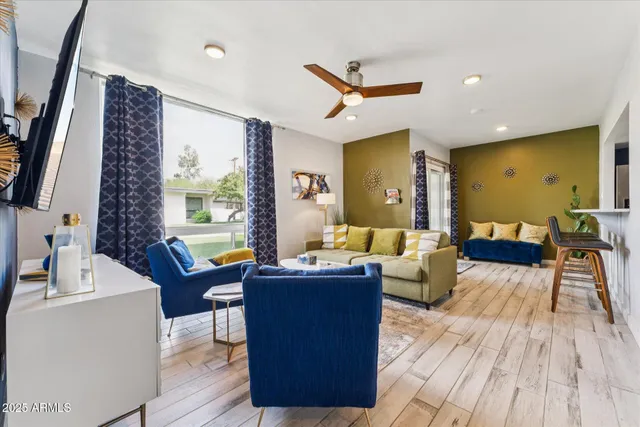 a living room with couches a flat tv screen and a dining table with wooden floor
