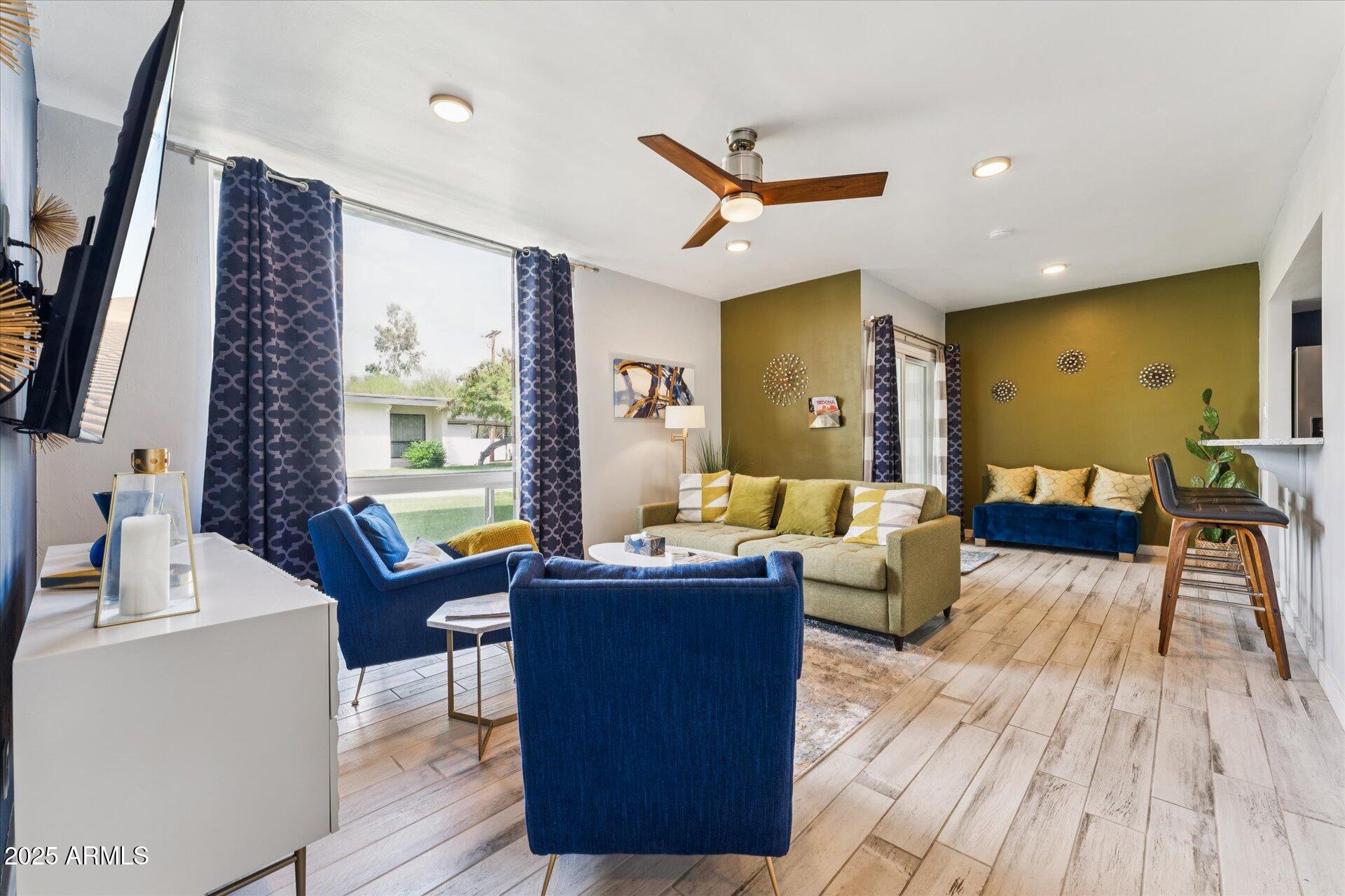 3242 East Camelback Road, Unit 105 Phoenix, AZ 85018 - Photo 3 of 24 a living room with couches a flat tv screen and a dining table with wooden floor