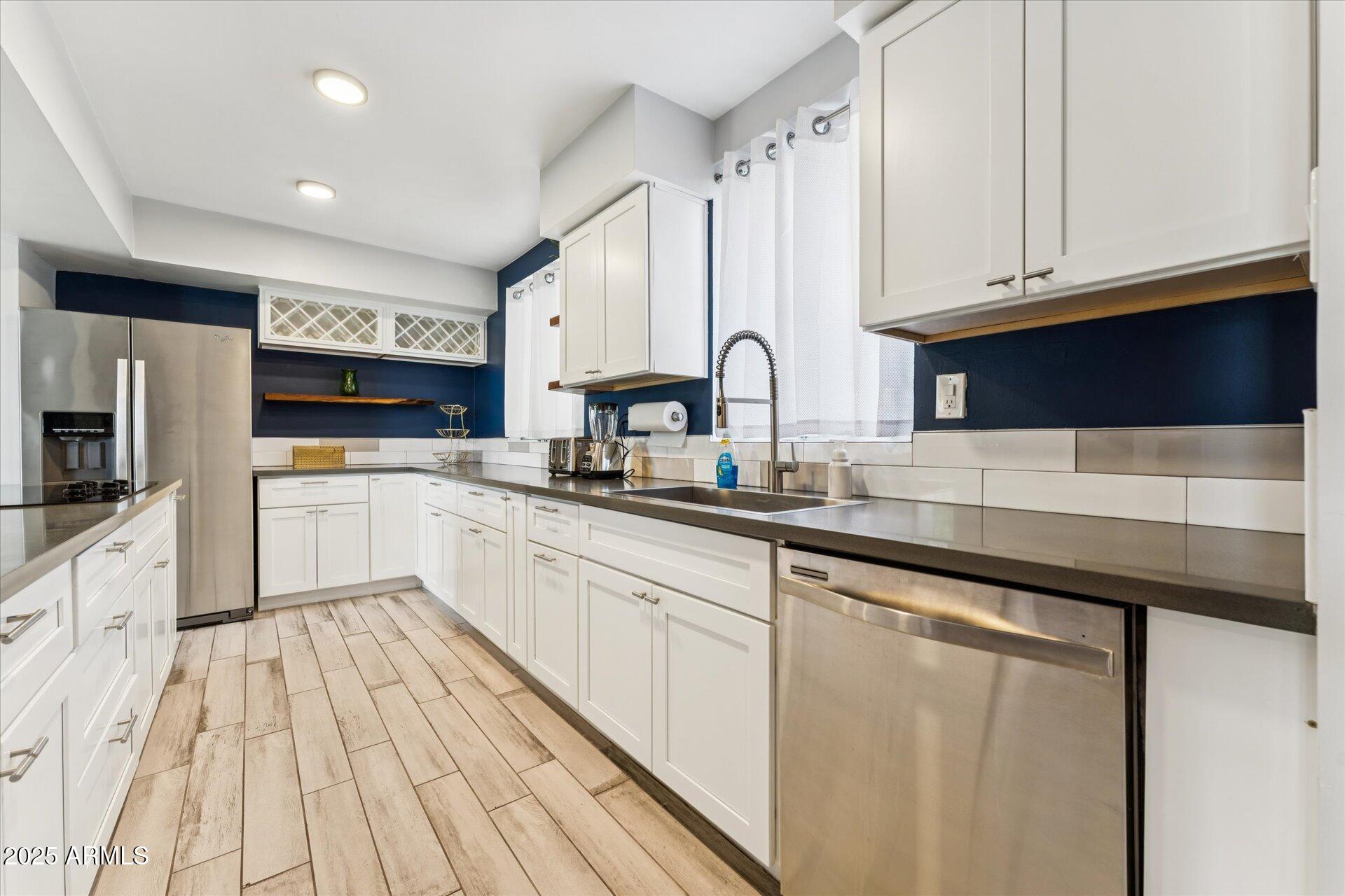 3242 East Camelback Road, Unit 105 Phoenix, AZ 85018 - Photo 5 of 24 a kitchen with stainless steel appliances granite countertop a refrigerator a sink dishwasher a stove and white cabinets with wooden floor