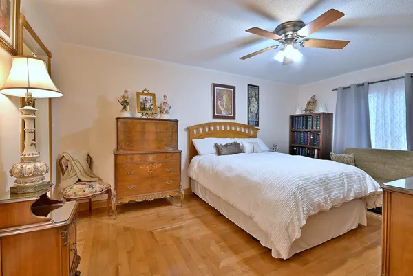 a spacious bedroom with a bed and dresser with wooden floor