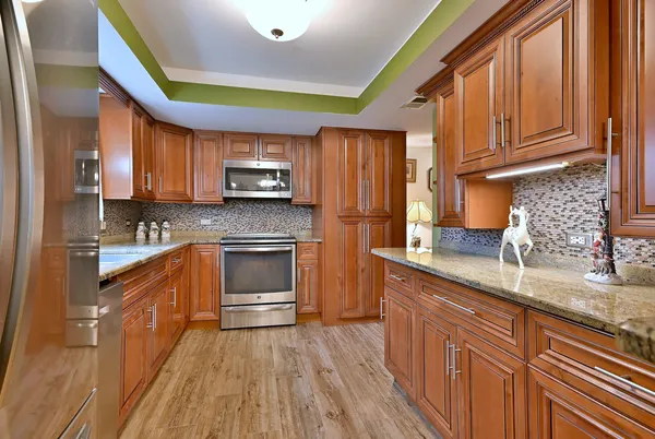 a kitchen with stainless steel appliances granite countertop wooden cabinets a stove top oven a sink and dishwasher