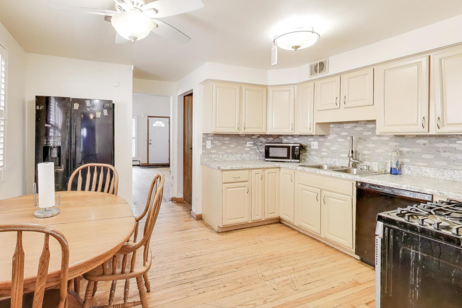 8622 South Michigan Avenue Chicago, IL 60619 - Photo 7 of 20 a kitchen with stainless steel appliances granite countertop a stove top oven a sink a dining table and chairs with wooden floor