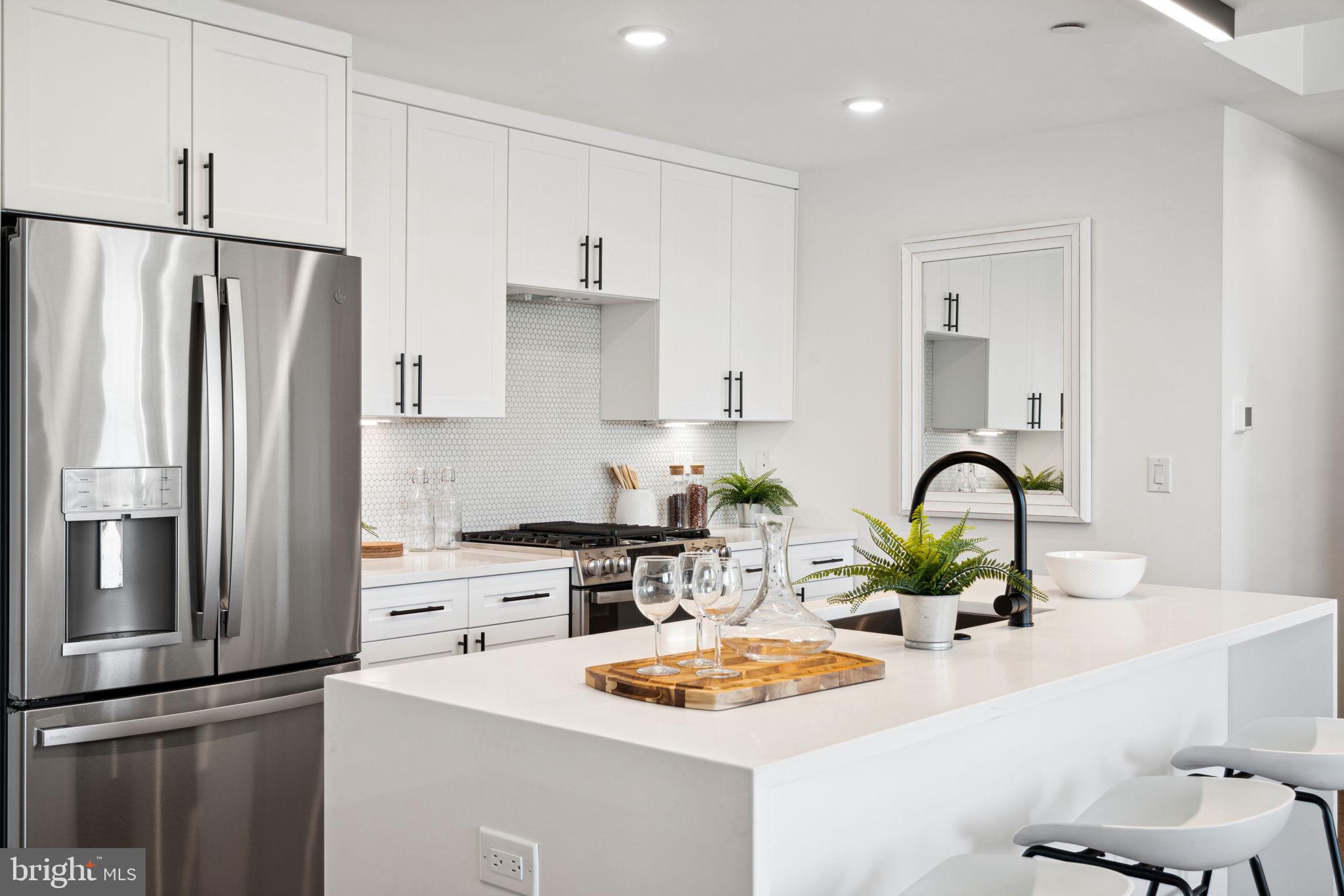 a kitchen with stainless steel appliances kitchen island a refrigerator sink and white cabinets