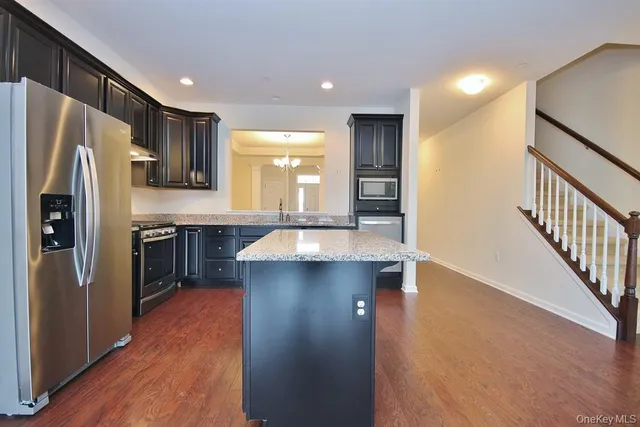 a kitchen with kitchen island granite countertop stainless steel appliances and wooden cabinets