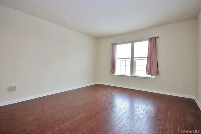 a view of an empty room with wooden floor and closet