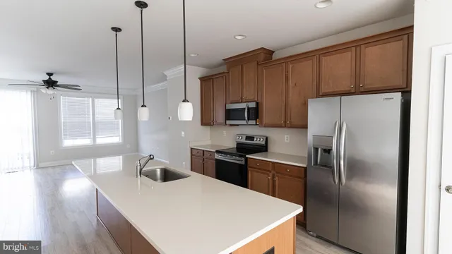 a kitchen with stainless steel appliances a refrigerator a sink a stove a table and chairs