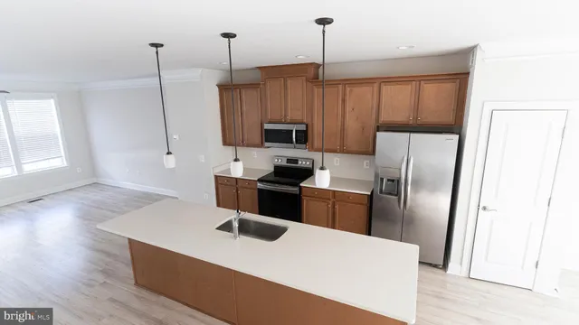 a kitchen with stainless steel appliances granite countertop a refrigerator a sink a stove and a wooden floors