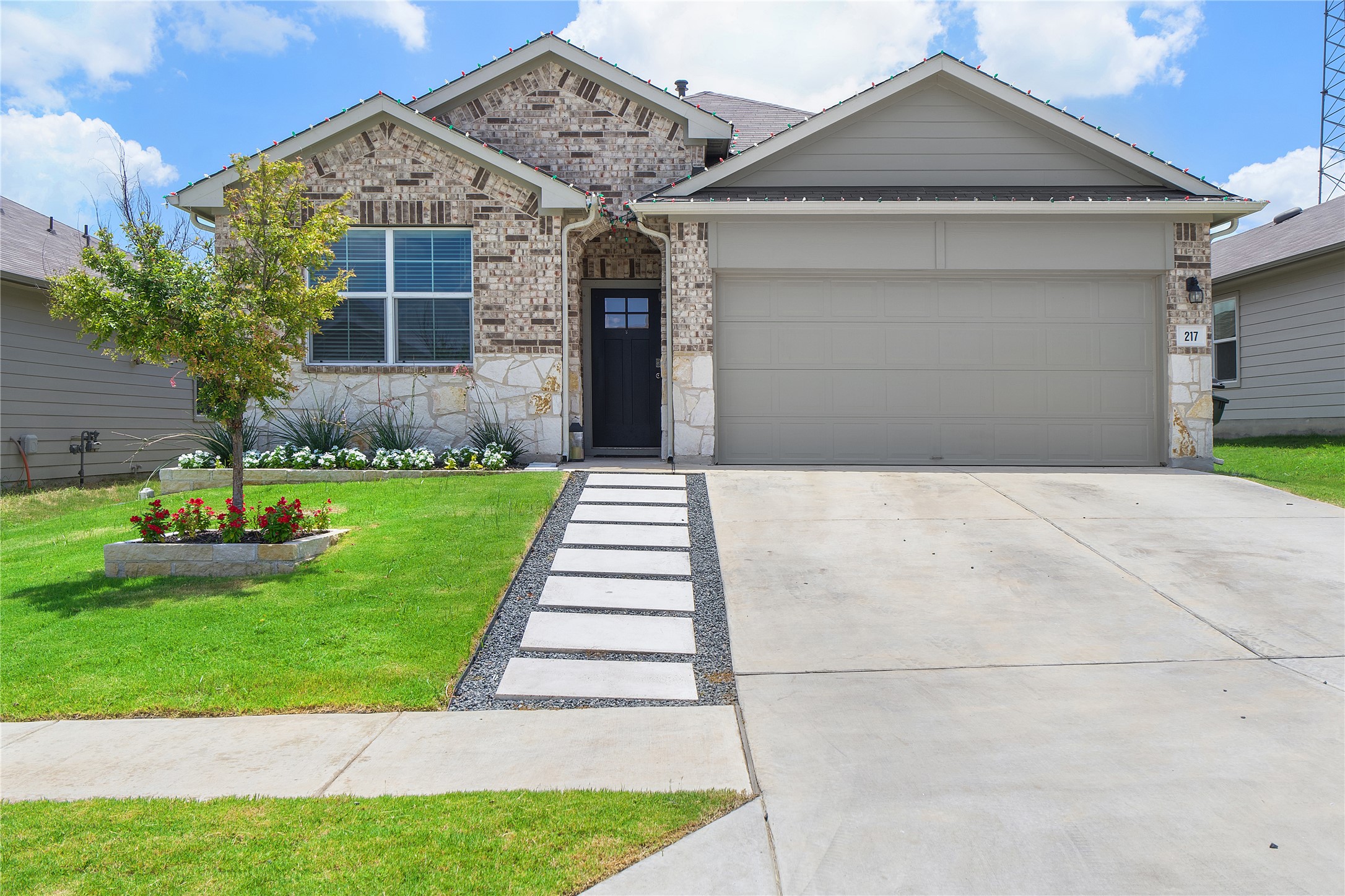 217 Evergreen Sumac Loop Kyle, TX 78640 - Photo 1 of 20 A well-maintained facade features a mix of brick and stone, welcoming with a landscaped walkway.