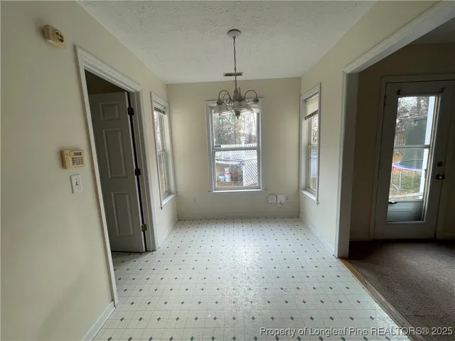 an empty room with ceiling fan and windows
