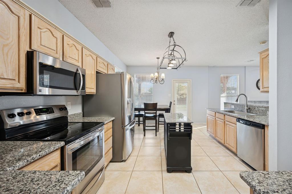 3304 Olympus Court Corinth, TX 76210 - Photo 14 of 40 a kitchen with stainless steel appliances granite countertop a stove top oven a sink dishwasher a dining table and chairs with wooden floor