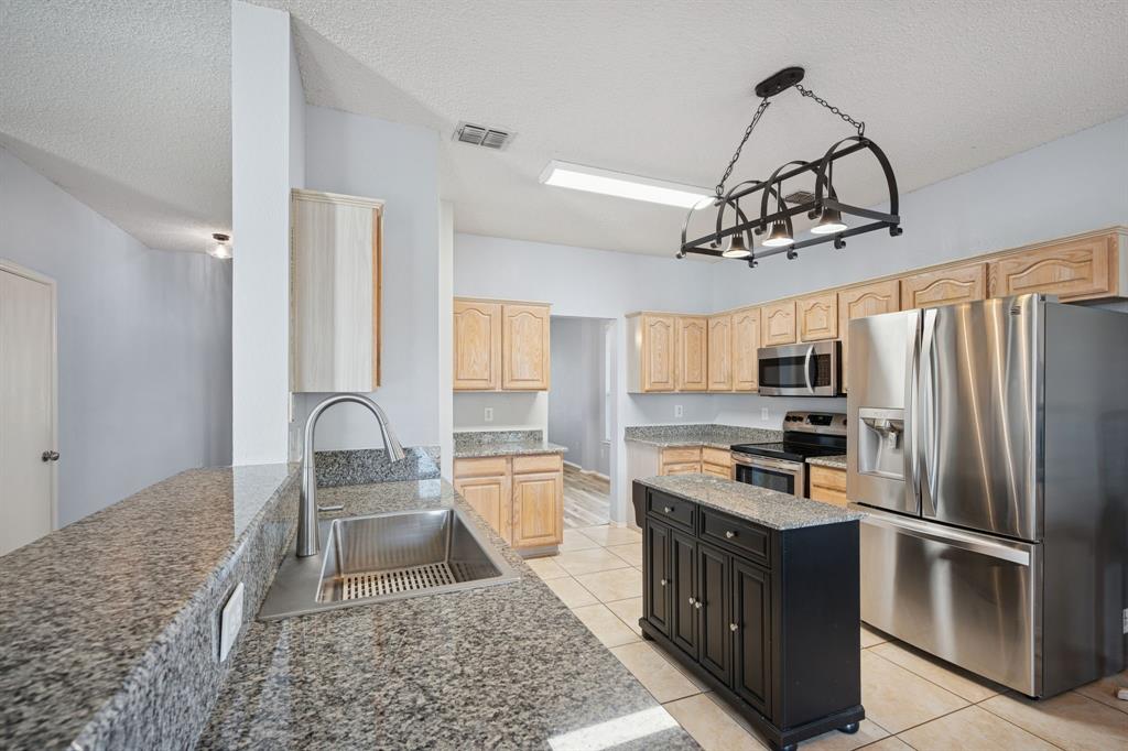 3304 Olympus Court Corinth, TX 76210 - Photo 15 of 40 a kitchen with stainless steel appliances granite countertop a sink a stove a refrigerator cabinets and chairs