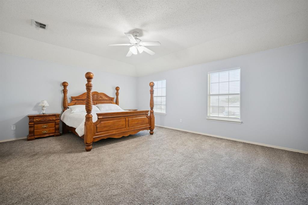 3304 Olympus Court Corinth, TX 76210 - Photo 23 of 40 a bedroom with a bed and a chandelier