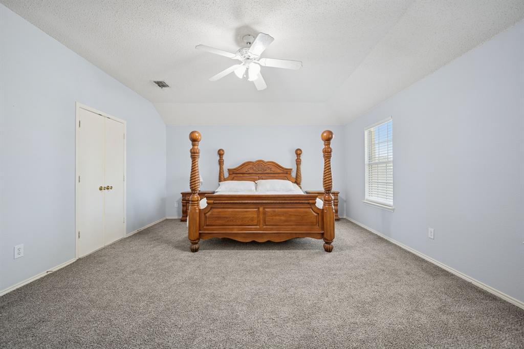 3304 Olympus Court Corinth, TX 76210 - Photo 24 of 40 a bedroom with a bed and a chandelier