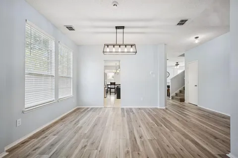 a view of a room with wooden floor chandelier and windows